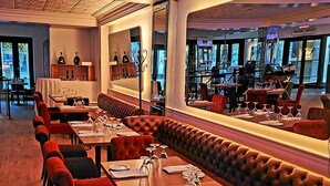 Ein Restaurant mit einem langen Esstisch, roten Sitzgelegenheiten mit Stoffbezug und einer Lederecke.
