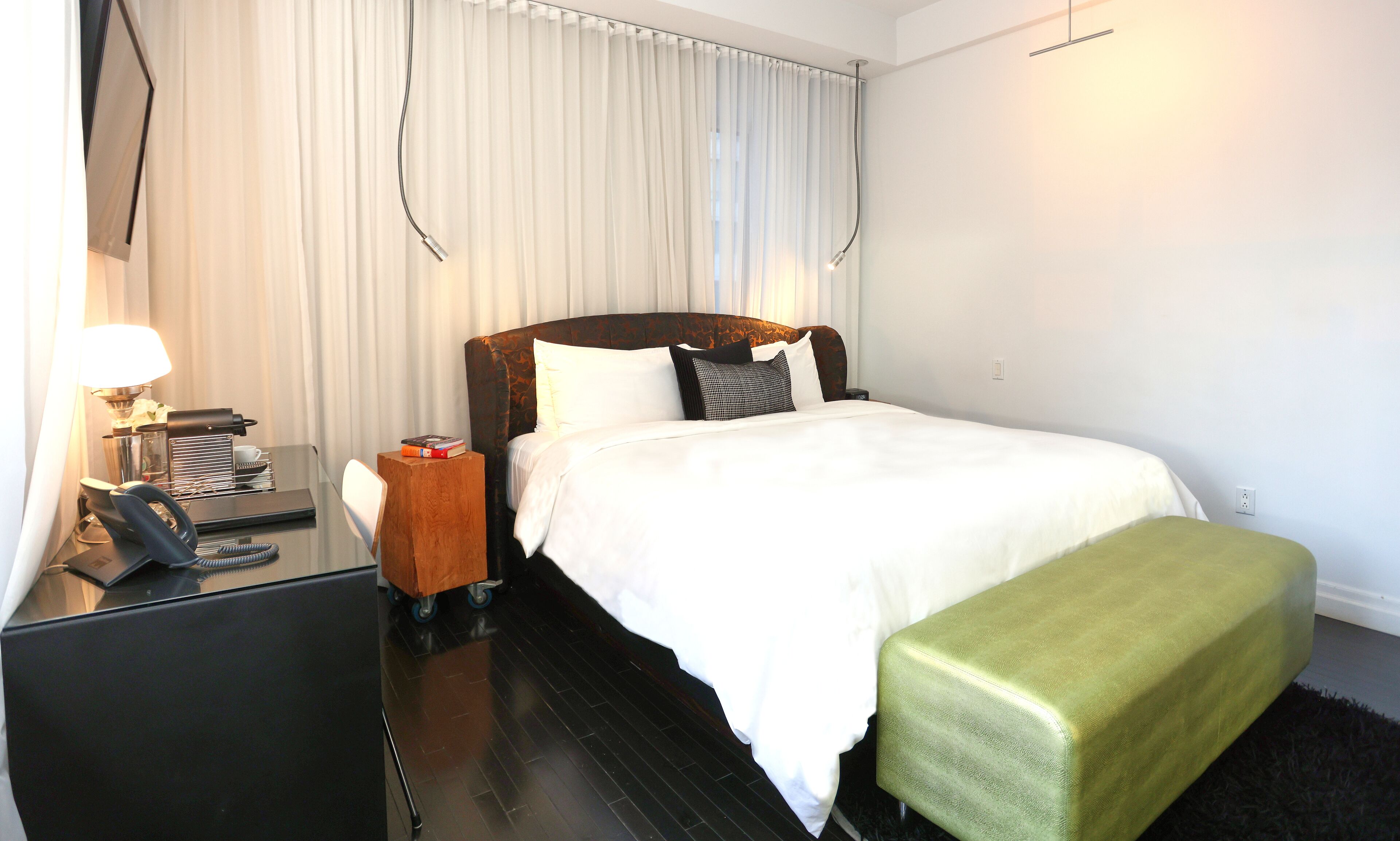 Una habitación de hotel con cama, mesita de noche, lámpara y teléfono.