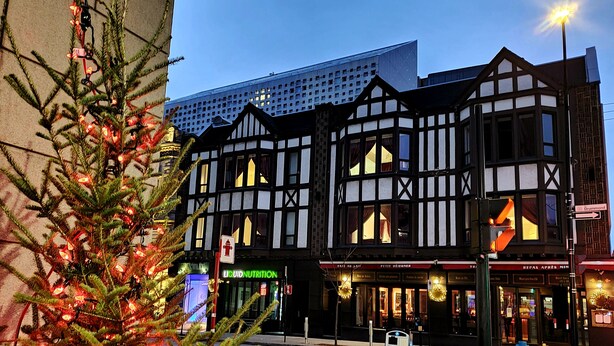 Ein traditionelles Tudor-Gebäude mit einer modernen Glasarchitektur darüber.