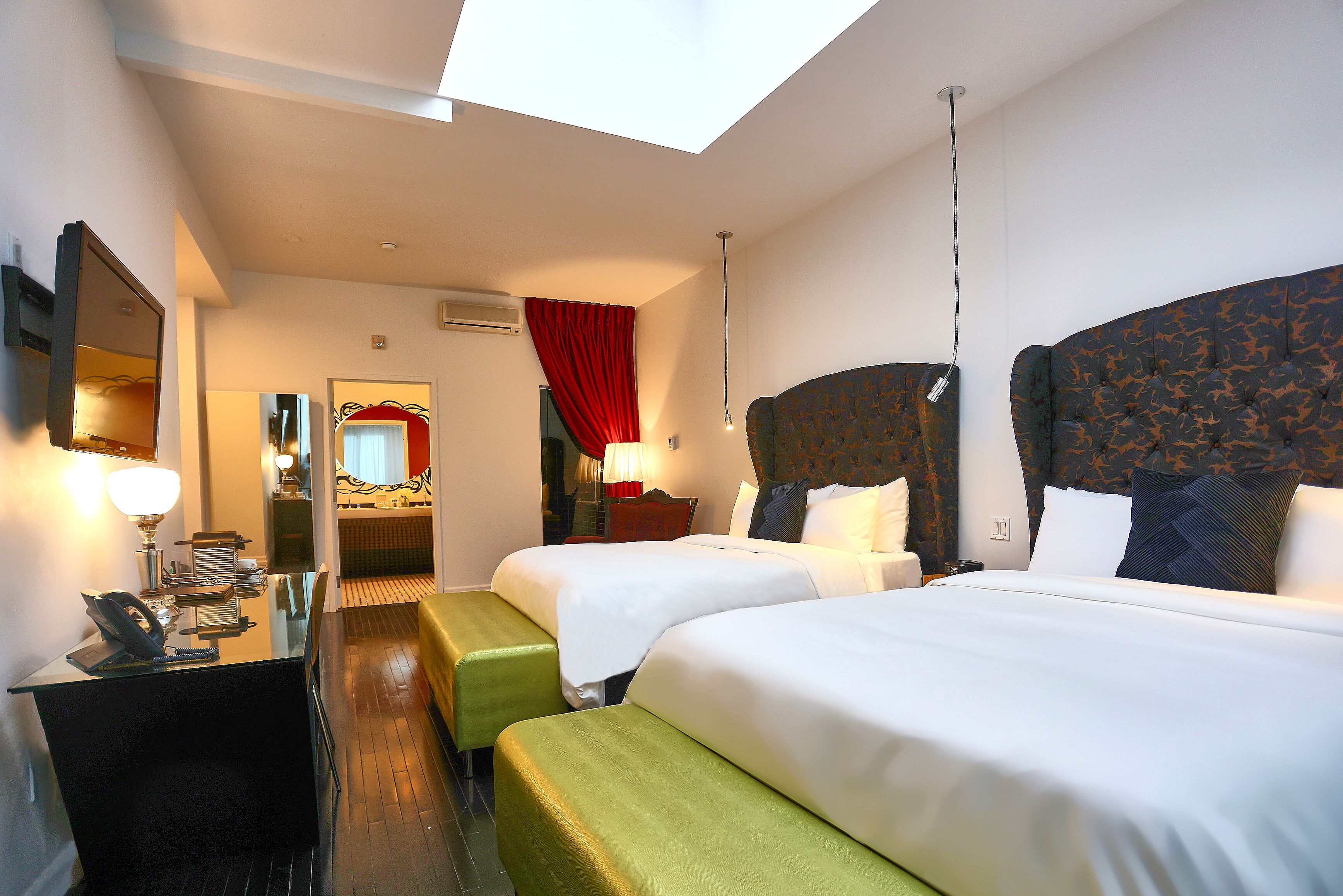 Habitación de hotel con dos camas, un escritorio con teléfono y un espejo.