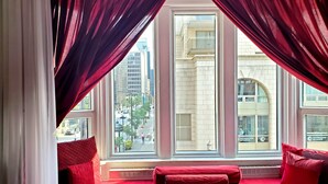 Ein Zimmer mit einer roten Couch und zwei Fenstern mit roten Vorhängen.