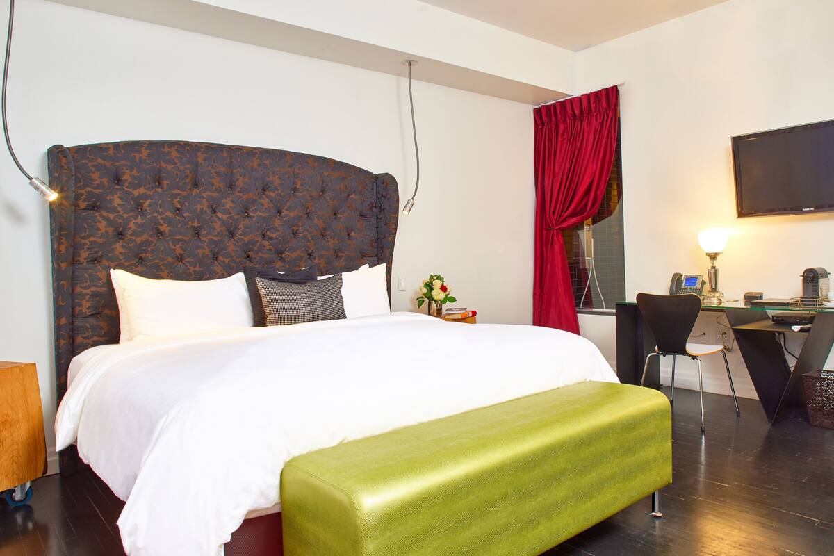 A hotel room with a large bed, a desk, and a chair.