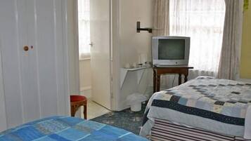 Habitación de hotel con cama, televisión, una mesita y una puerta que da a otra habitación.