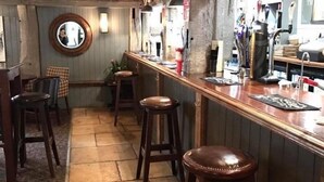 Zona de bar con taburetes de madera, un espejo y equipo para bar.