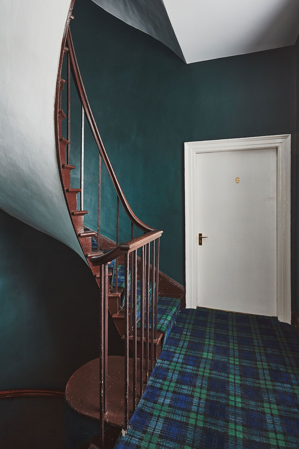 A staircase with a wooden handrail leading to a door marked with the number 6.