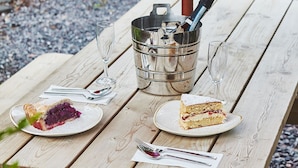 Ein Holztisch für ein Picknick mit zwei Kuchenplatten und einem Champagnerkühlbag.
