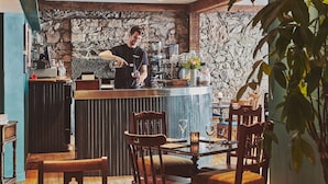Eine Bar mit einer Steinsäule, Holzmöbeln und einem Barista, der Getränke zubereitet.