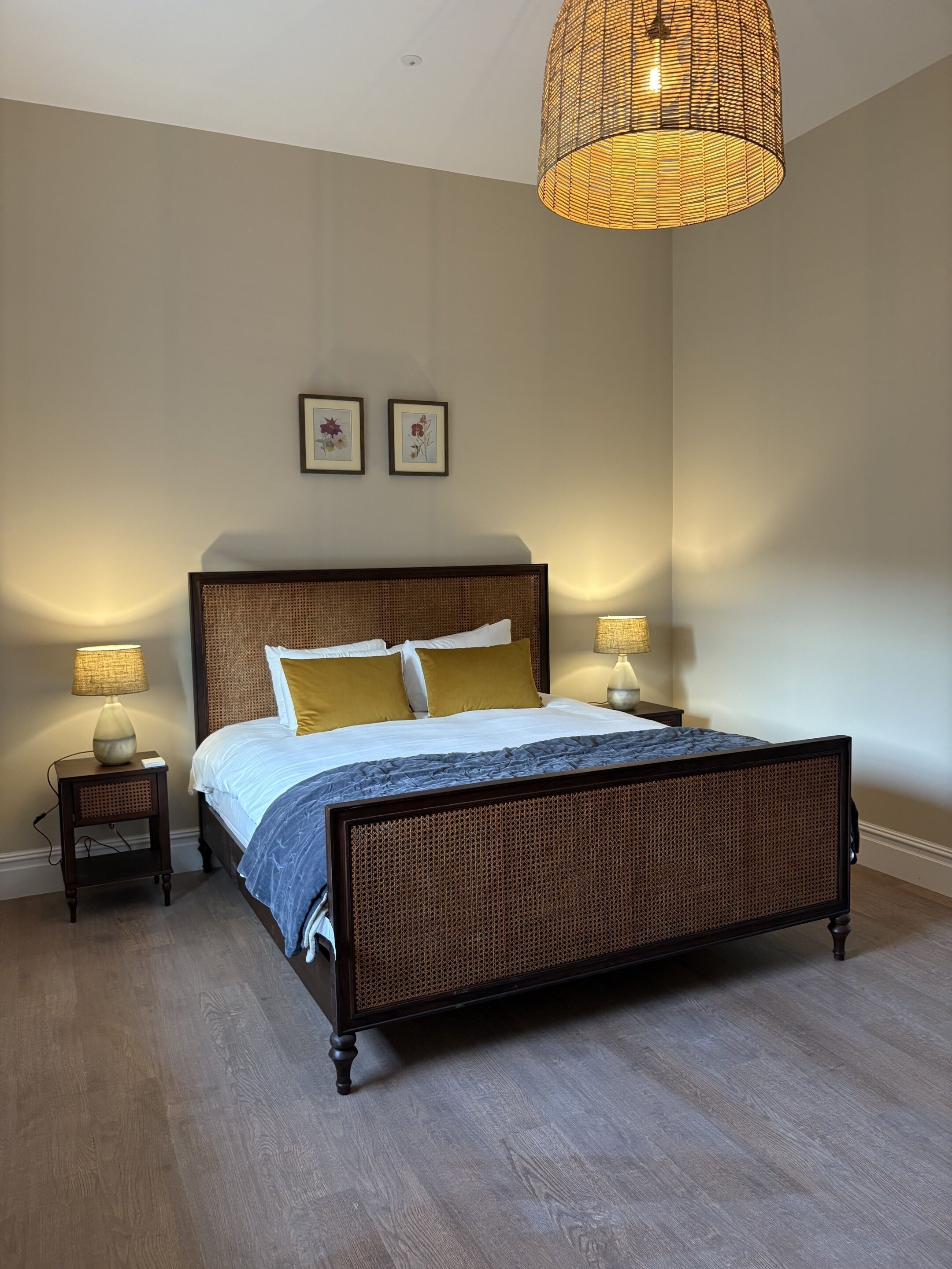 Un dormitorio con una cama grande, dos lámparas de noche y una lámpara colgante.