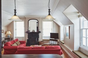 A cozy living room with a red sofa, a fireplace, and a television.