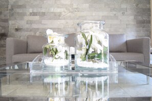 Two glass jars with white flowers on a glass table. - St Andrews Boutique Hotel (Germiston)
