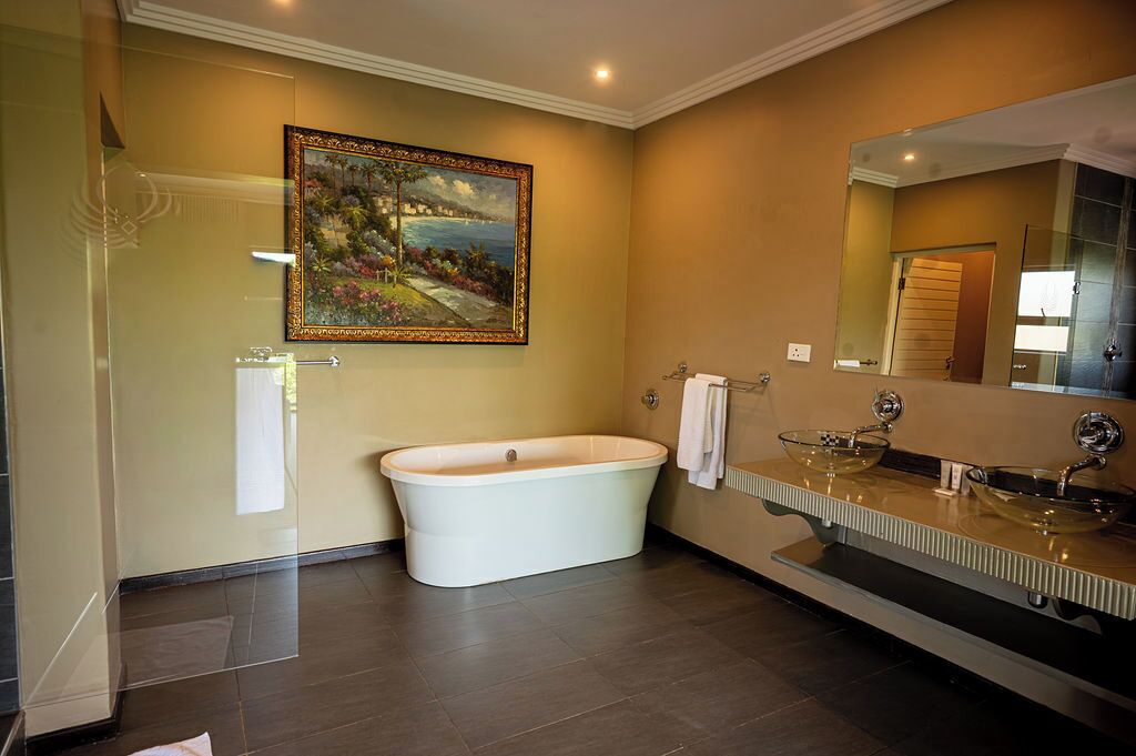 Une salle de bain avec une baignoire sur pieds, un grand miroir et un tableau accroché au mur.