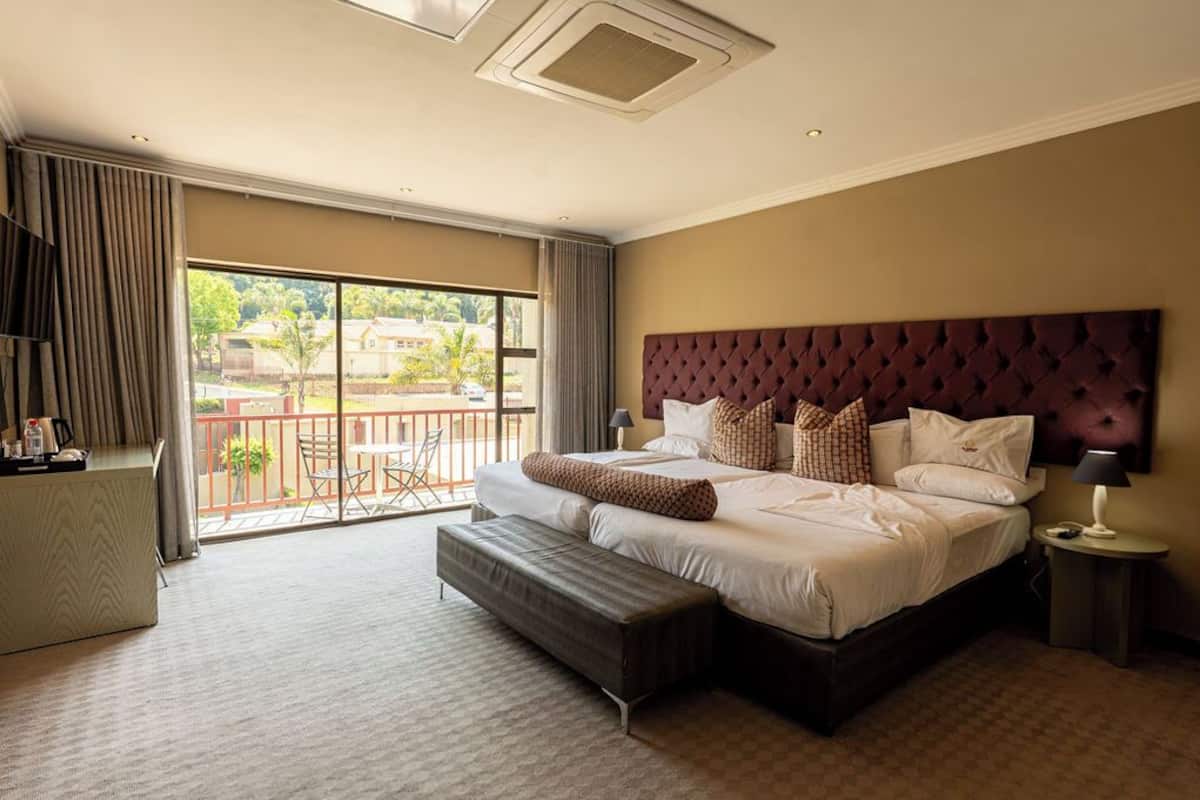 Een ruime hotelkamer met een groot bed, een balkon met uitzicht en een bureau met stoel.