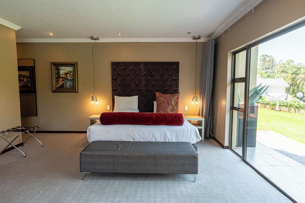 Ein Schlafzimmer mit einem großen Bett, einer grauen Bank, einem Kopfteil und einem Bild an der Wand.