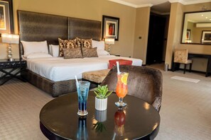 A hotel room with a large bed, a round table with drinks, and a chair. - St Andrews Boutique Hotel (Germiston)