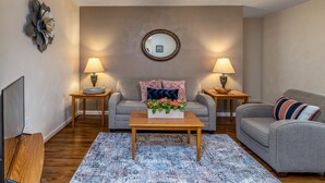 Ein Wohnzimmer mit einer Couch, zwei Beistelltischen, einem Couchtisch und einem Spiegel an der Wand.