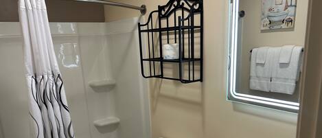 A bathroom with a shower, toilet, sink, and a towel rack.