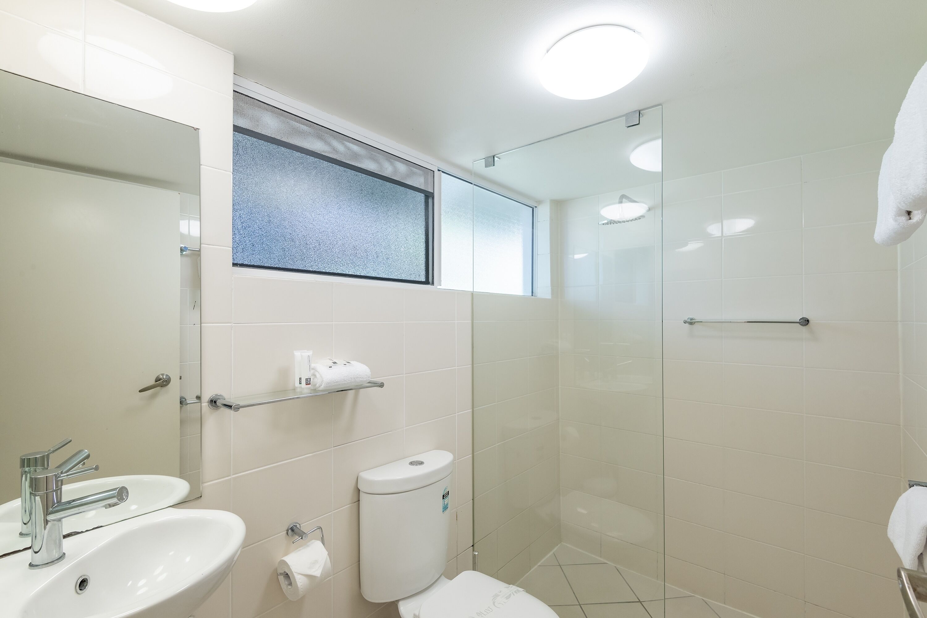 A modern bathroom with a sink, toilet, and glass shower enclosure.