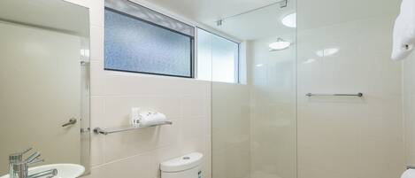A modern bathroom with a sink, toilet, and glass shower enclosure.
