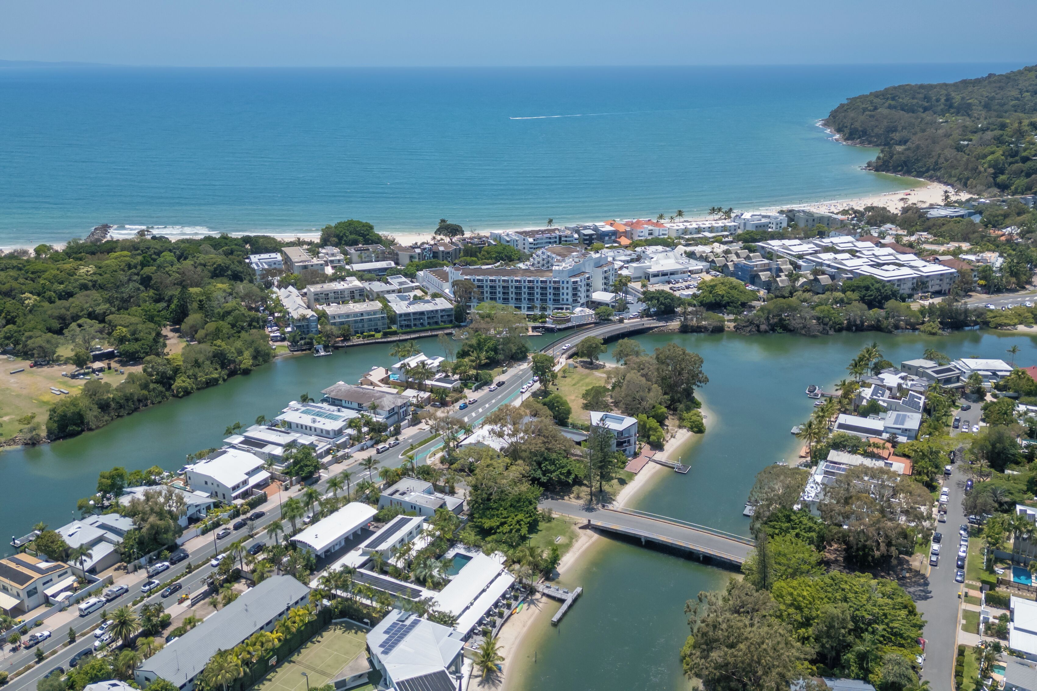 An aerial view of a coastal town with buildings, a bridge, and a beach.