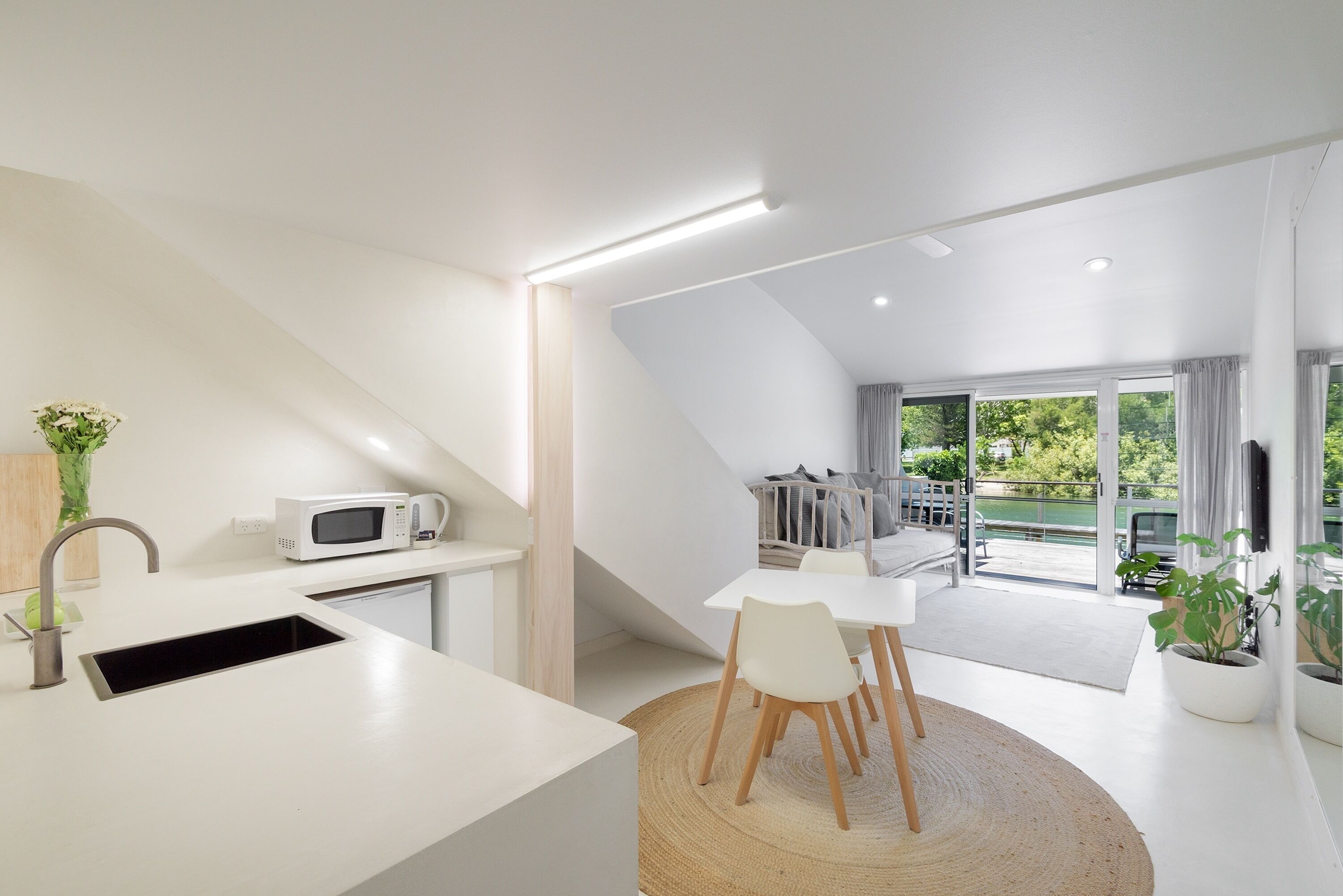 A modern kitchen with a built-in microwave, a sink, and a dining area with chairs.