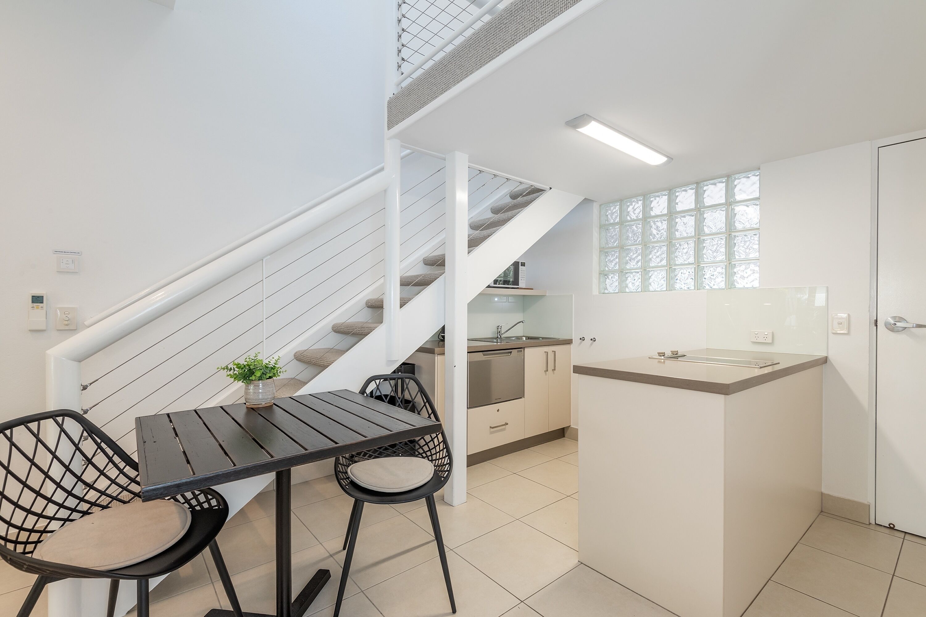 Une cuisine moderne avec un coin repas, comprenant un escalier, un petit îlot central et une vue sur la ville.