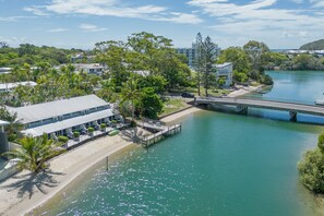 A riverside hotel with a bridge, a beach, and lush greenery. - Caribbean Noosa (Noosa Heads)