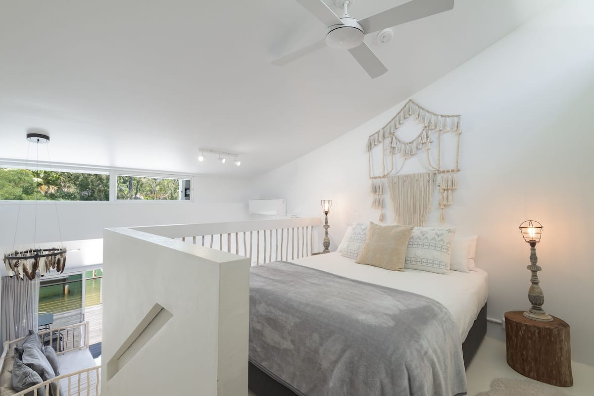 A modern bedroom with a large bed, a ceiling fan, and a view of the outdoors.