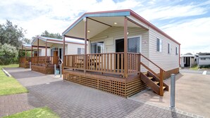 A mobile home with a porch, wooden deck, and a covered outdoor area. - Gateway Lifestyle Birubi Beach (Anna Bay)