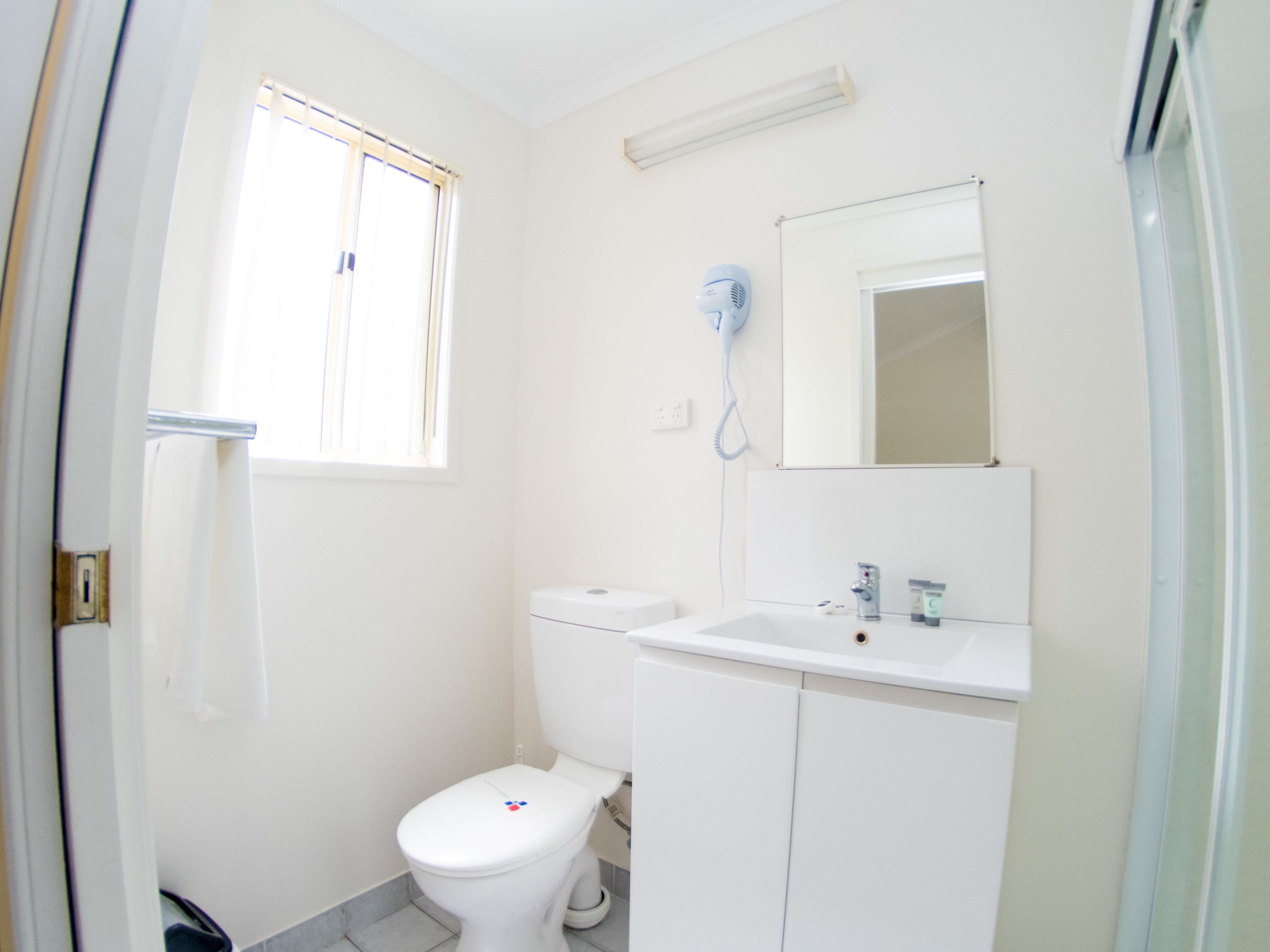 Une petite salle de bain propre, équipée de toilettes, d’un lavabo et d’un miroir.