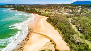 Un pueblo costero con una playa arenosa, abundante vegetación y edificios residenciales.