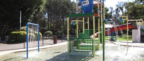 Une aire de jeux avec un espace dédié aux jeux d’eau, un enclos clôturé et un panneau indiquant « BONNY HILLS ».