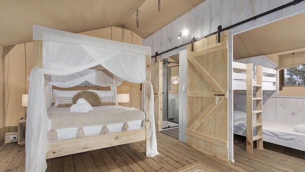 Un dormitorio con cama con dosel, suelo de madera y una puerta grande de madera.