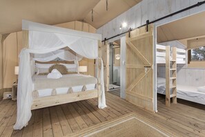 A bedroom with a canopy bed, wooden flooring, and a large wooden door. - Ingenia Holidays Bonny Hills (Bonny Hills)