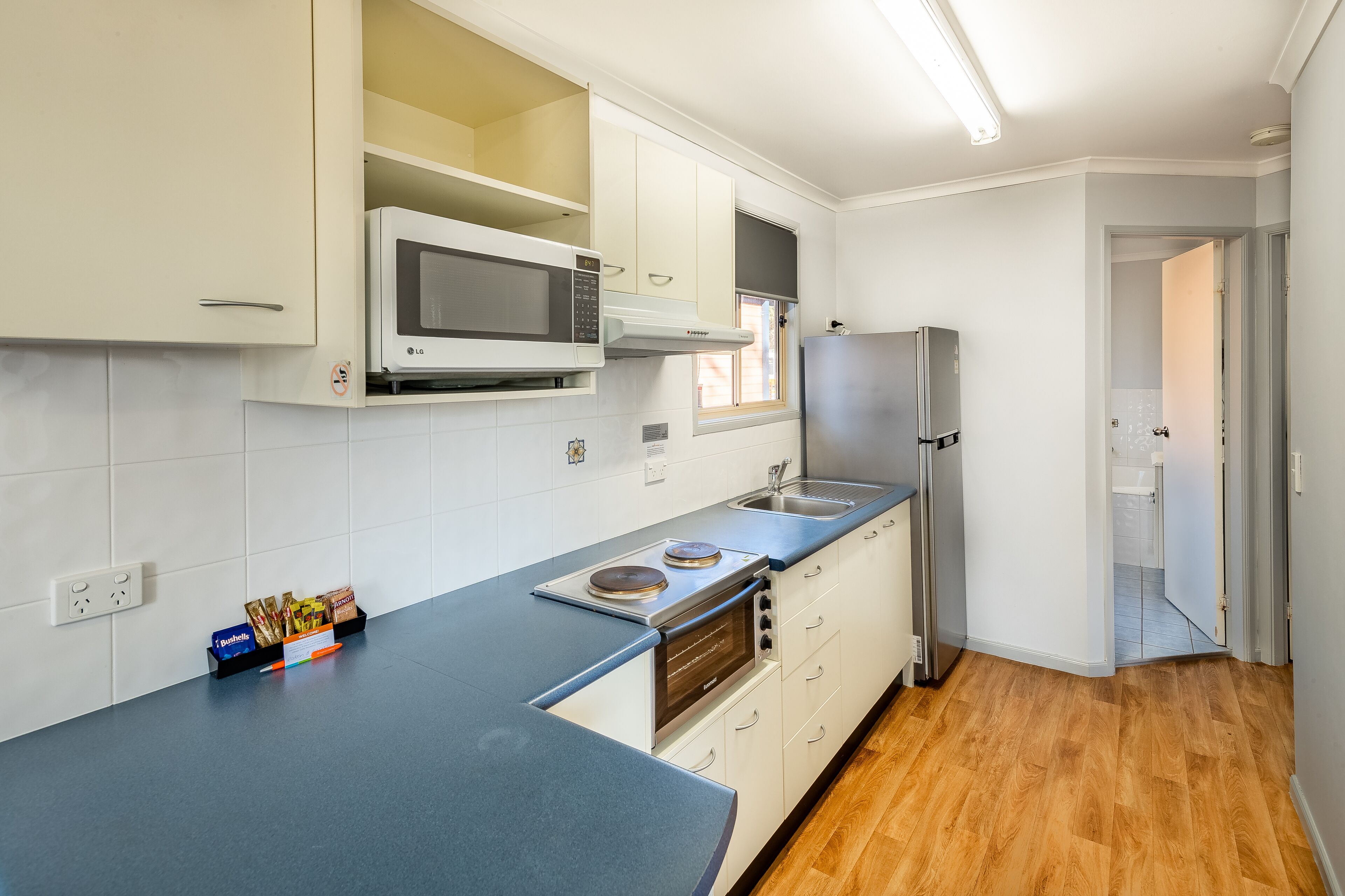 A modern kitchen with white cabinets, a built-in microwave, a stove, and a refrigerator.