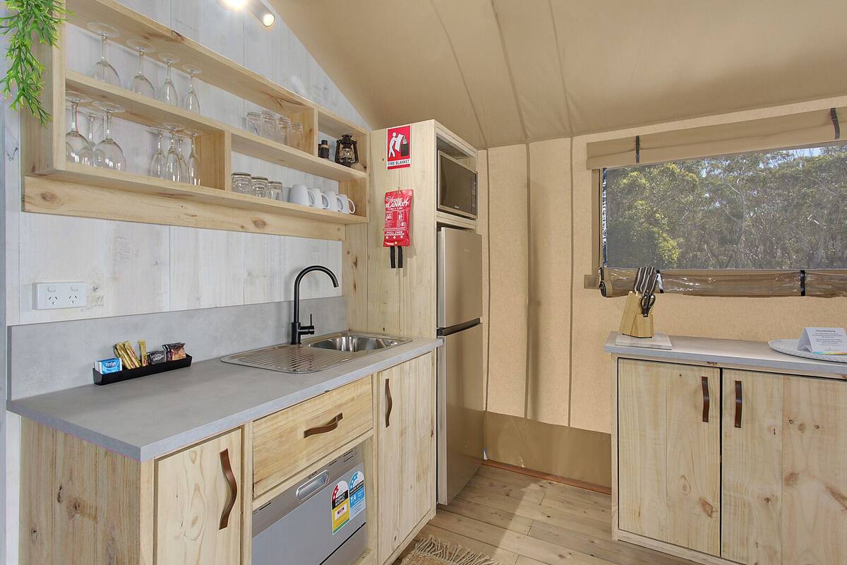 Una cocina moderna con armarios de madera, un lavamanos de acero inoxidable y un horno empotrado.