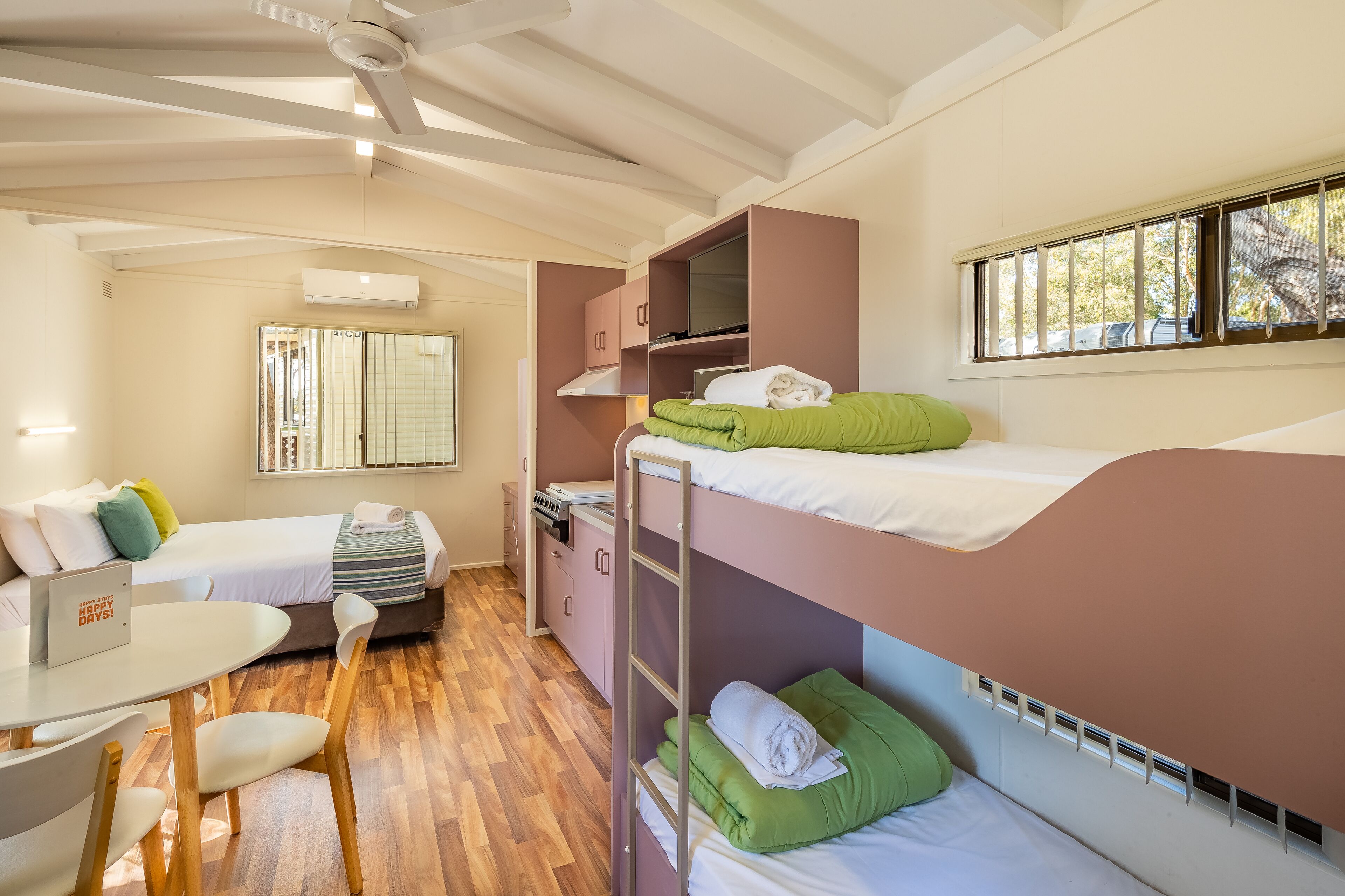 Une chambre d’hôtel de taille réduite, équipée de lits superposés, d’un bureau et d’une chaise.