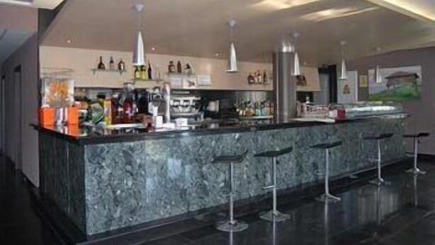 A modern bar area with a marble countertop, multiple bar stools, and pendant lighting. - Cuatro Hermanas (Sagunto)