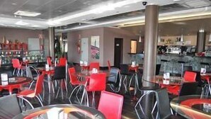 A modern restaurant with red and black chairs, round tables, and a visible counter area. - Cuatro Hermanas (Sagunto)