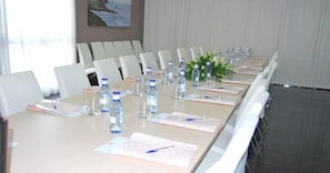 Ein Konferenzraum mit einem langen Tisch, Stühlen, Wasserflaschen und Unterlagen.