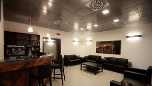 Een moderne lounge met een bar, leren banken en een koffieapparaat.