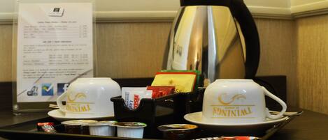 A tray with two cups labeled "TWINNIL," a coffee pot, and a menu sign in a hotel setting.