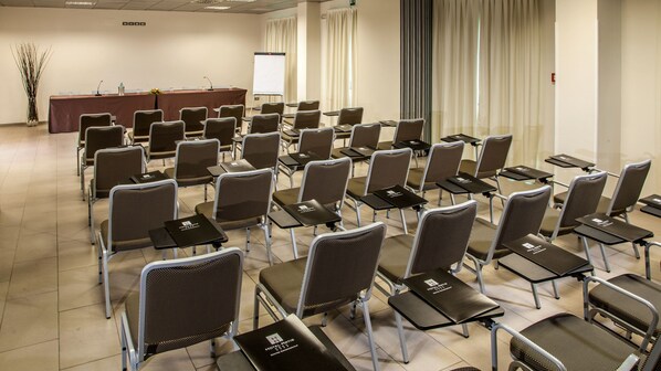 A conference room with rows of chairs and tables, a podium, and a projector screen. - Hotel Artis (Rome)