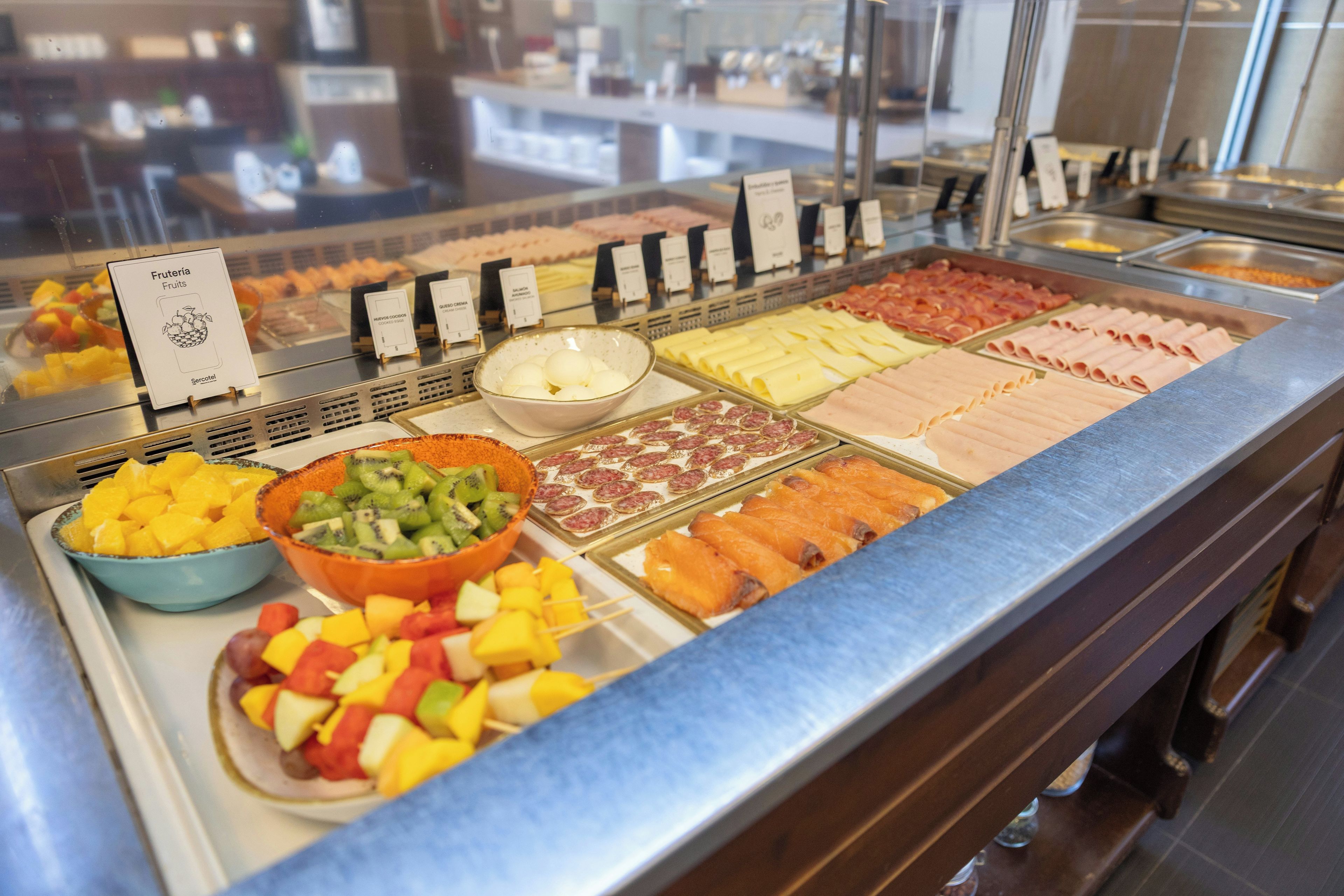 Un buffet proposant une variété de plats, notamment des fruits, des fromages et des viandes.