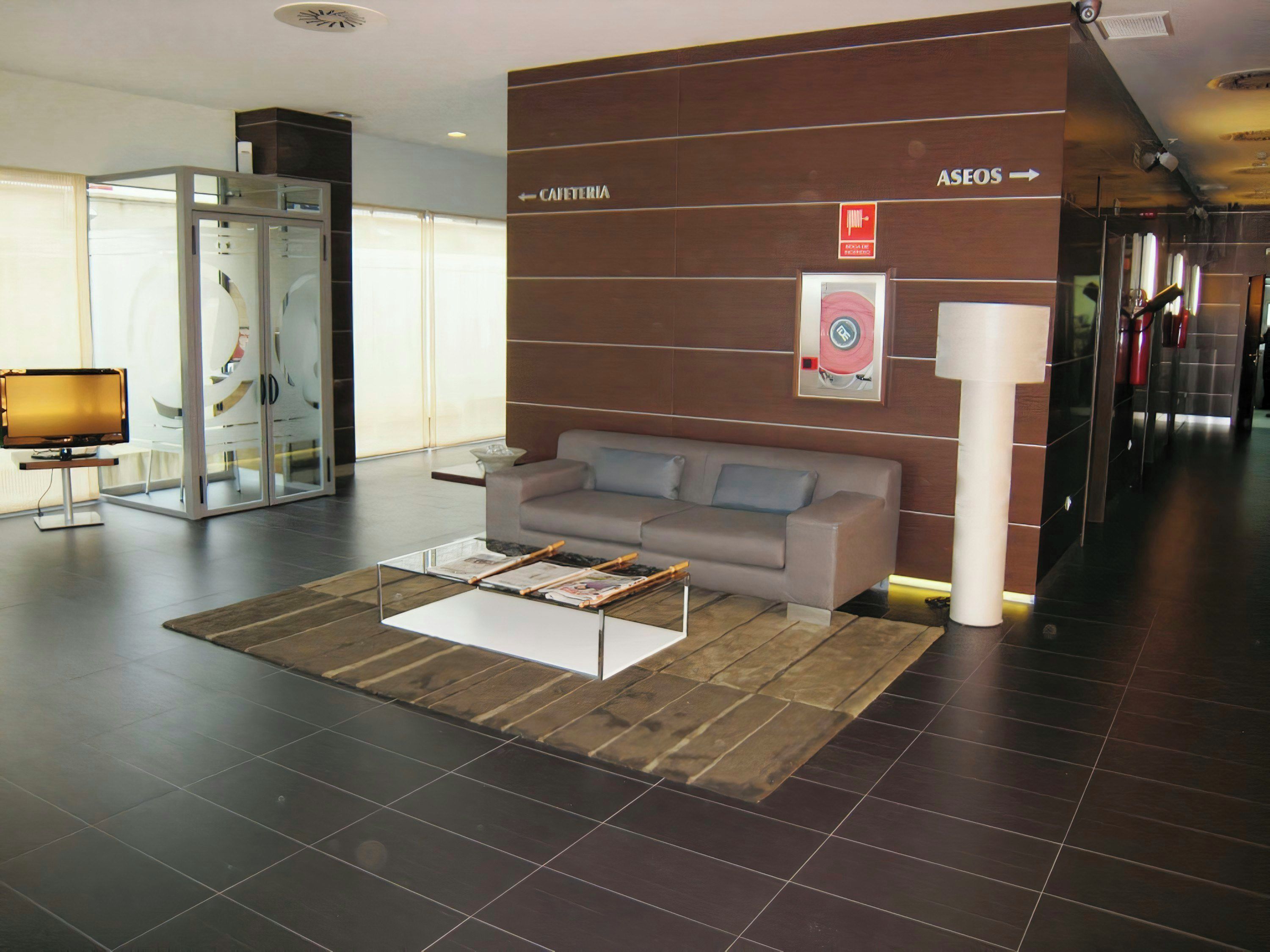 A modern lobby with a sofa, a coffee table, and a glass partition.