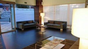 A hotel lobby with two sofas, a coffee table, and a glass display case. - Sercotel Aura Algeciras (Algeciras)