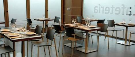 A restaurant interior with tables set for dining, chairs, and a large window with frosted glass.