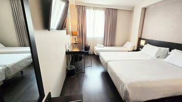 Een hotelkamer met twee bedden, een bureau, een stoel, een televisie en een raam met gordijnen.