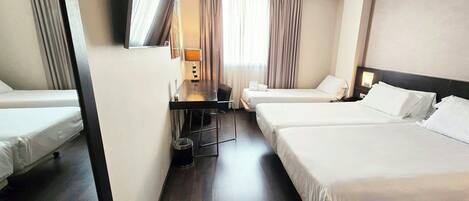 A hotel room with two beds, a desk, a chair, a TV, and a window with curtains.