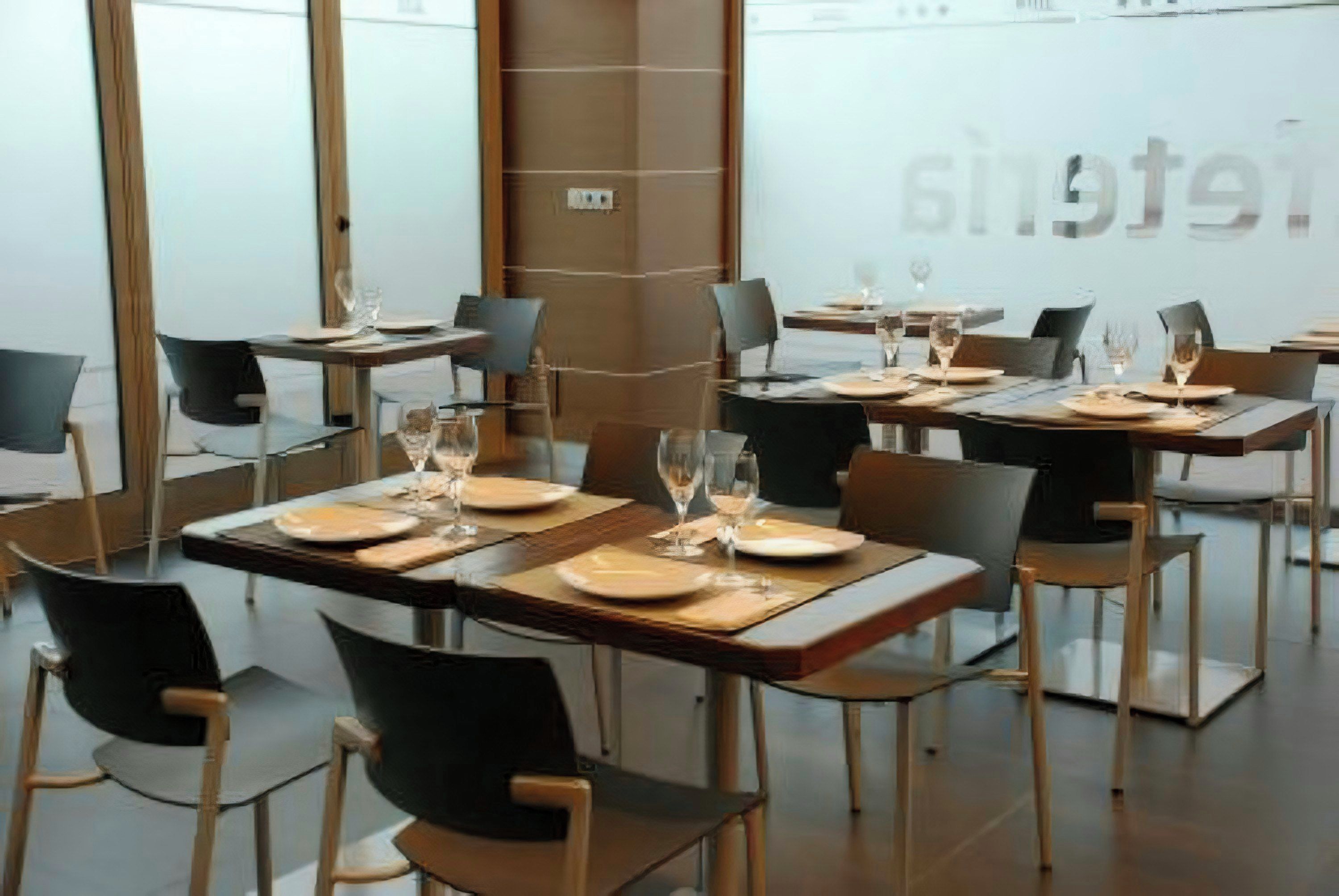 A modern hotel dining area with tables set for dining, chairs, and a large window.