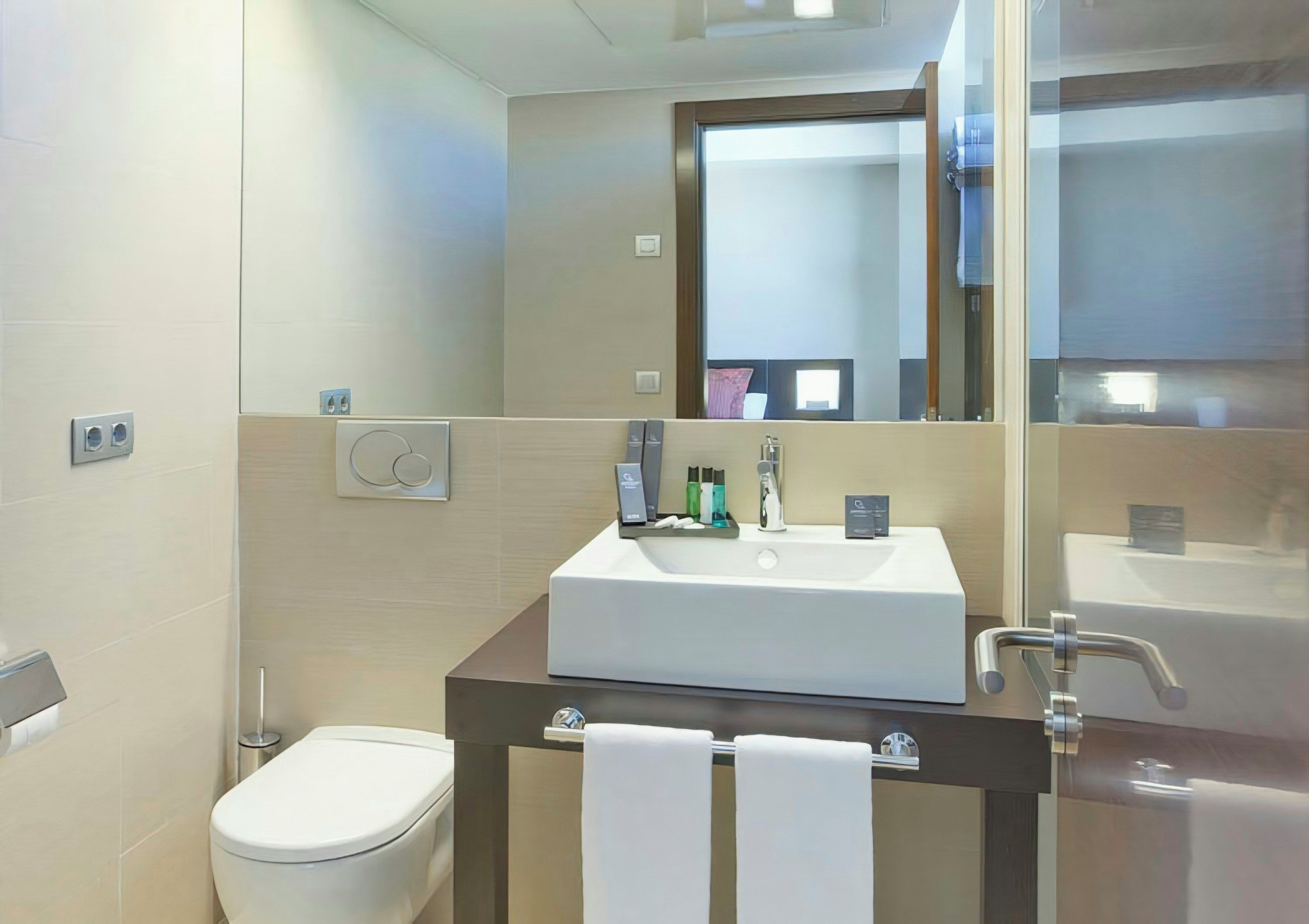 A modern bathroom with a white sink, mirror, and toilet.